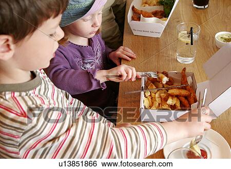 Stock Photograph - Boy and girl eating fish and chips. Fotosearch