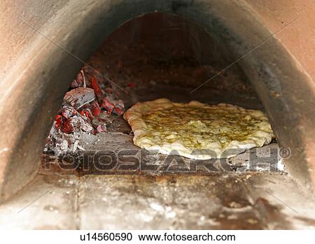 Stock Image - Pizza being cooked, a clay oven. Fotosearch
