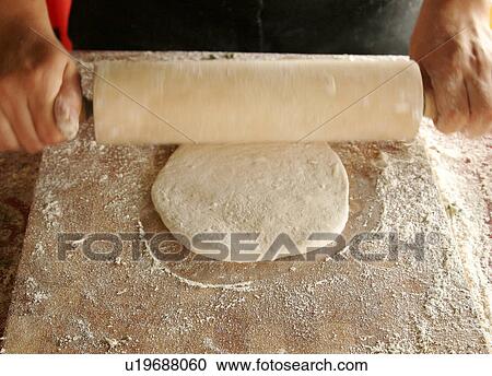 Stock Image - Rolling naan bread dough. Fotosearch