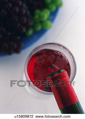 Stock Image - Poured Red Wine and Grape, High Angle View. Fotosearch