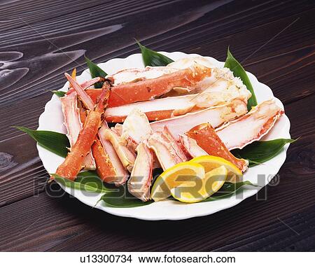 Boiled legs of crab with lemons on plate, high angle view View Large Photo Image Picture - Boiled legs of crab with lemons on plate, high angle view. Fotosearch