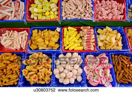 Stock Image - A variety of meatballs and fishballs in trays, on display at a market stall. Fotosearch