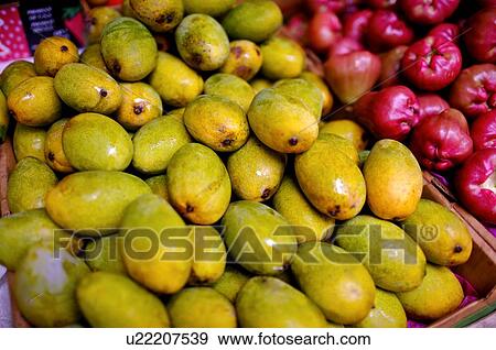 Stock Photo - Pile of mangoes on display in a box, next to a box of water apples. Fotosearch