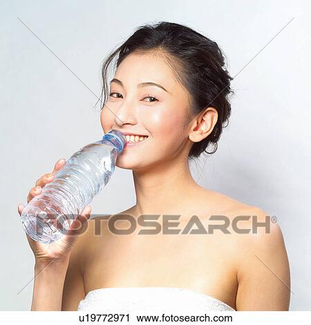 Stock Image - Asian woman drinking water out of a bottle . Fotosearch