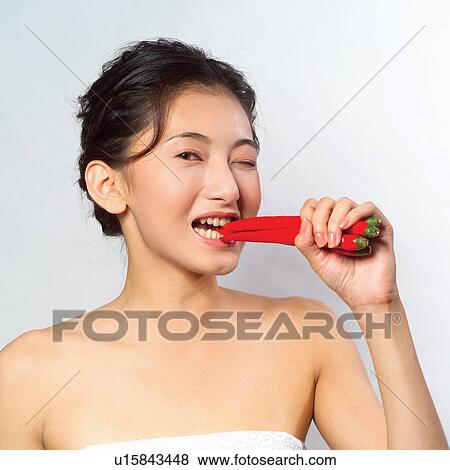 Stock Photo - Chili Pepper, Heat, Health & Beauty, Biting, Holding, Healthy Lifestyle. Fotosearch