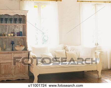 Picture -  a Living Room With a White-colored Couch and a Wooden Cabinet, Front View. Fotosearch