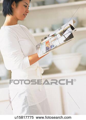a Mid Adult Woman Reading a Magazine in the Kitchen, Side View, Differential Focus View Large Photo Image Stock Photography - a Mid Adult Woman Reading a Magazine in the Kitchen, Side View, Differential Focus. Fotosearch