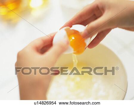 Picture -  a Person Breaking an Egg and Adding It to a Bowl, High Angle View, Differential Focus. Fotosearch