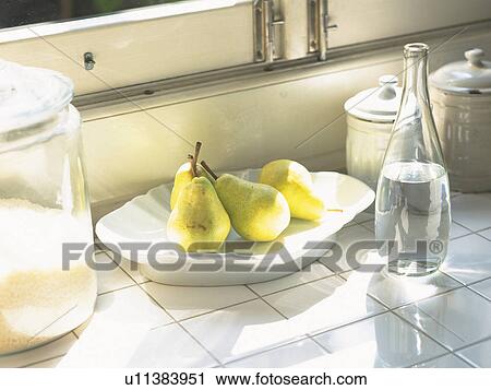 Stock Image -  a Plate With Several Pears, Next to a Bottle and Some Pots, High Angle View. Fotosearch