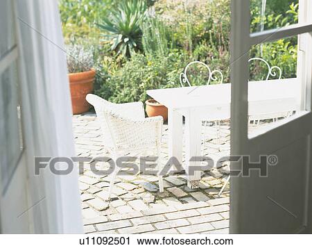 Stock Image -  a White Table and Chair Standing Outside, a White Door Visual, High Angle View. Fotosearch
