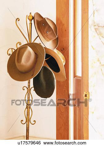 Stock Photograph -  Several Hats Hanging on a Golden Hanger Near a Door. Fotosearch