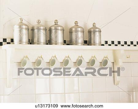 Several Metal Container Standing on a White Banquette, With White Cups Hanging Under It, Low Angle View View Large Photo Image Stock Photo - Several Metal Container Standing on a White Banquette, With White Cups Hanging Under It, Low Angle View. Fotosearch