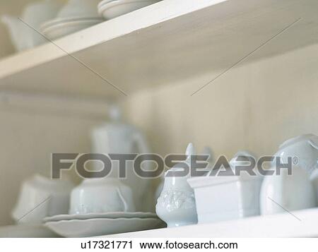 Stock Image -  Several White Porcelain Dishes Standing in a Cupboard, Side View, Differential Focus. Fotosearch