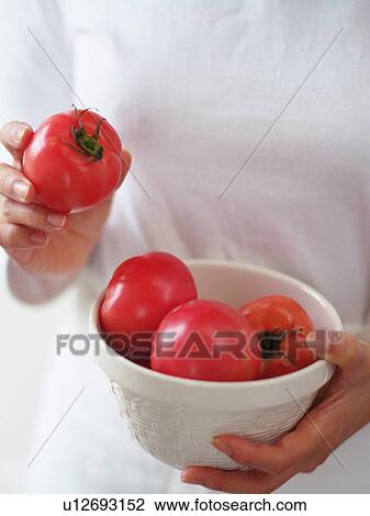 Stock Image -  Someone Holding a Bowl Full of Tomatoes, One in the Right Hand, High Angle View. Fotosearch