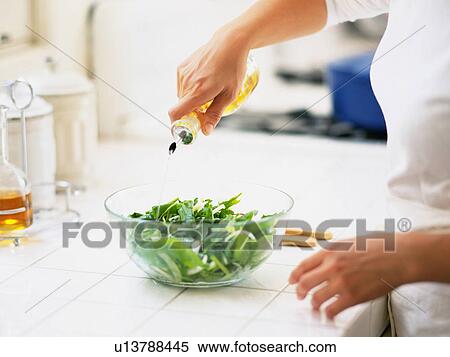 Stock Photography -  Someone Putting Some Oil in a Green Salad, Side View. Fotosearch