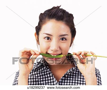 Stock Photo - A Woman Biting Wheat, Looking at Camera, Front View. Fotosearch