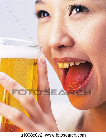 Stock Image - A Woman Drinking Beer, Smiling, Side View, Close Up,. Fotosearch