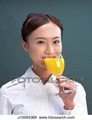Stock Photo - A Woman Drinking Glass of Juice, Looking at Camera, Front View . Fotosearch