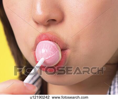 Stock Image - A Woman Eating a Lollipop, Front View, Close Up. Fotosearch