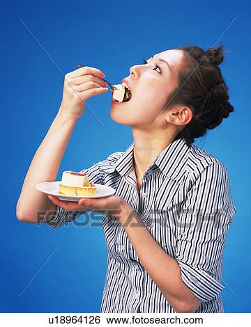 Stock Photograph - A Woman Eating Cake, Side View, . Fotosearch