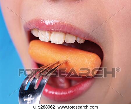 Stock Image - A Woman Eating Carrot, Front View, Close Up. Fotosearch