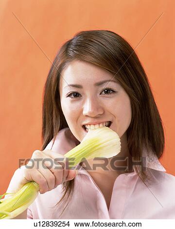Picture - A Woman Eating Celery, Looking at Camera, Front View . Fotosearch