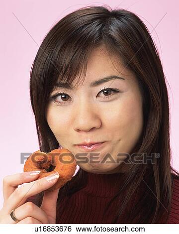 Stock Photograph - A Woman Eating Doughnut, Smiling, Looking at Camera, Front View . Fotosearch
