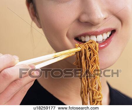 Stock Photo - A Woman Eating Fried Noodle, Front View, Close Up. Fotosearch