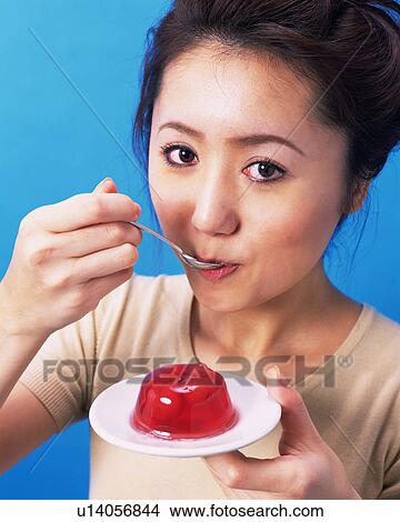 Picture - A Woman Eating Jell-O, Looking at Camera, High Angle View. Fotosearch