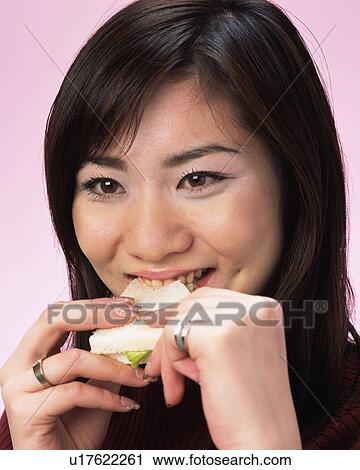 Stock Image - A Woman Eating Sandwich, Front View . Fotosearch