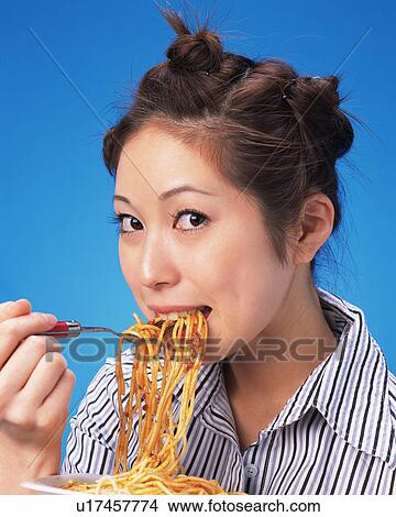 A Woman Eating Spaghetti, Looking at Camera, Side View View Large Photo Image Picture - A Woman Eating Spaghetti, Looking at Camera, Side View. Fotosearch