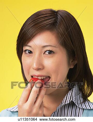 Picture - A Woman Eating Strawberry, Looking at Camera, Front View, . Fotosearch