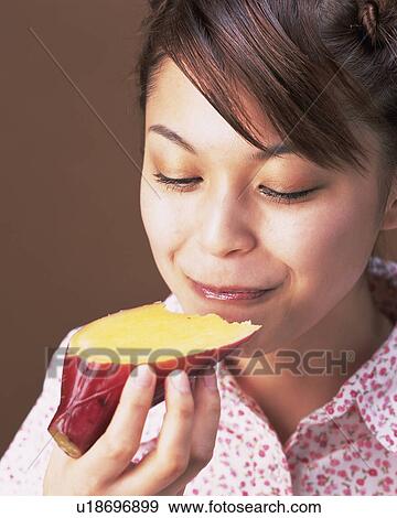 Stock Photo - A Woman Eating Sweet Potato, High Angle View . Fotosearch