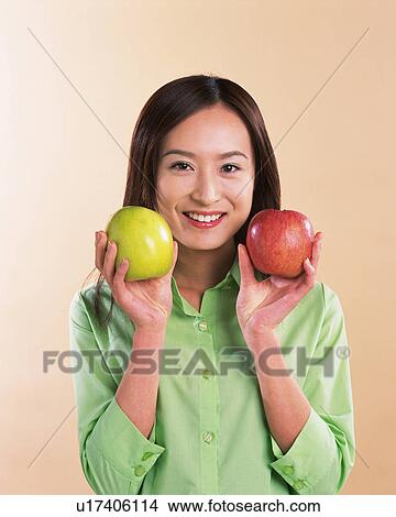 Picture - A Woman Holding Apple, Smiling, Looking at Camera, Front View . Fotosearch