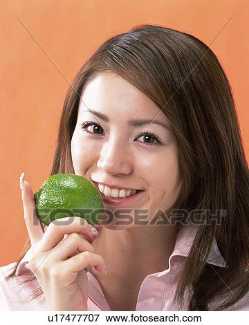 Stock Photo - A Woman Holding Lime, Smiling, Looking at Camera, Front View . Fotosearch
