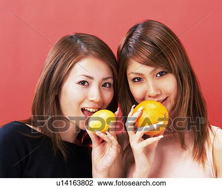 Two Young Women Eating Orange and Lemon, Looking at Camera, Front View, View Large Photo Image Stock Image - Two Young Women Eating Orange and Lemon, Looking at Camera, Front View,. Fotosearch