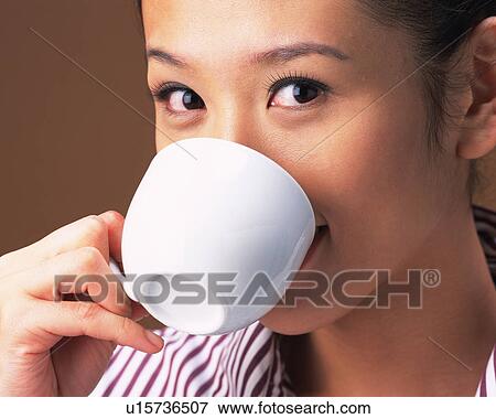 Stock Photo - Young Woman Drinking a Coffee, Smiling, Looking at Camera, Side View. Fotosearch