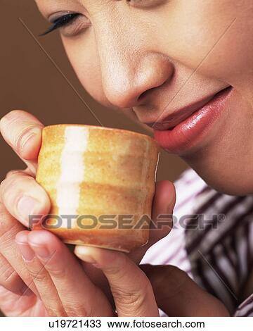 Stock Image - Young Woman Drinking Sake, Smiling, Side View, Close Up. Fotosearch