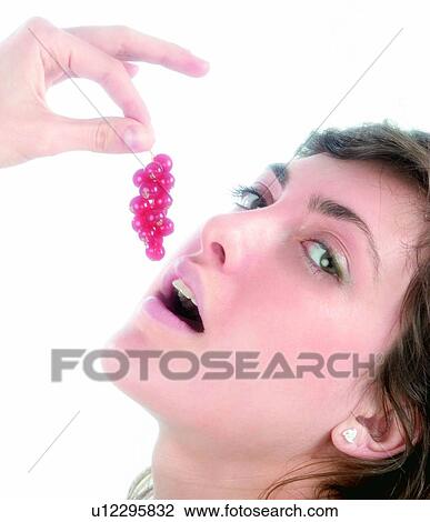 Stock Image - Woman, Brown hair, Beauty, White undershit, White, Red Currant Berry, Opening mouth. Fotosearch