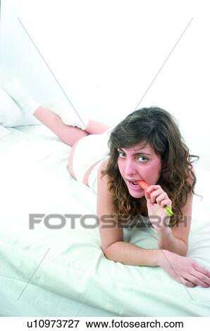 Woman, Brown hair, Beauty, White undershit, White, Carrot, Biting View Large Photo Image Stock Photo - Woman, Brown hair, Beauty, White undershit, White, Carrot, Biting. Fotosearch