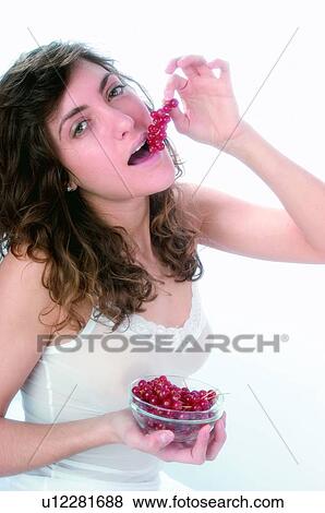 Stock Photo - Woman, Brown hair, Beauty, White undershit, White, Red Currant Berry, Opening mouth. Fotosearch