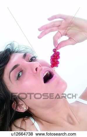 Stock Photo - Woman, Brown hair, Beauty, White undershit, White, Red Currant Berry, Opening mouth. Fotosearch