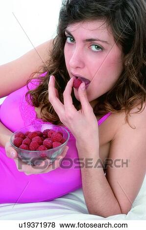 Stock Photo - Woman, Brown hair, Beauty, White undershit, White, Red Currant Berry, Opening mouth. Fotosearch