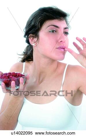 Stock Photography - Woman, Brown hair, Ponytail, Beauty, White undershit, Red Currant Berry, Eating. Fotosearch