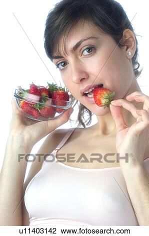 Stock Image - Woman, Brown Hair, Beauty, White undershit, Eating, Fruit, Strawberry. Fotosearch