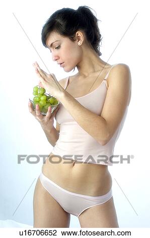 Stock Image - Woman, Brown Hair, Beauty, White undershit, Eating, Fruit, Grapes. Fotosearch