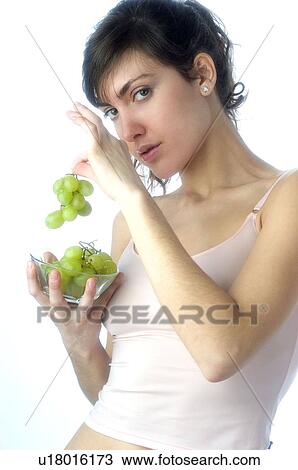 Stock Image - Woman, Brown Hair, Beauty, White undershit, Eating, Fruit, Grapes. Fotosearch