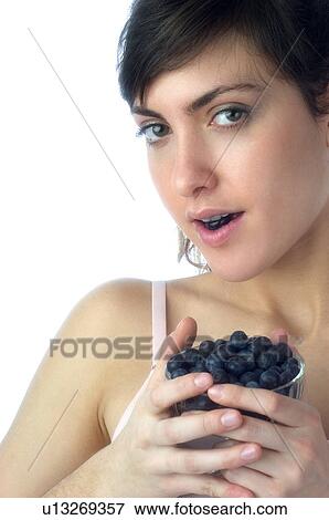 Stock Photo - Woman, Brown Hair, Beauty, White undershit, Eating, Fruit, Blueberry. Fotosearch
