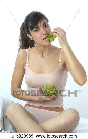 Stock Photo - Woman, Brown Hair, Beauty, White undershit, Eating, Fruit, Grapes. Fotosearch