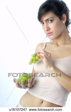 Stock Photo - Woman, Brown Hair, Beauty, White undershit, Eating, Fruit, Grapes. Fotosearch